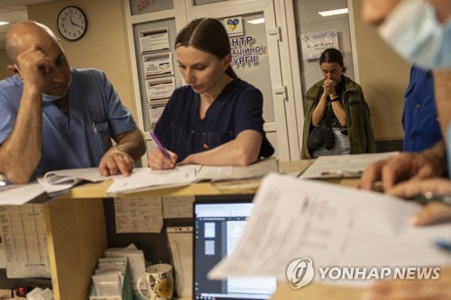 우크라이나 드니프로의 병원에서 한 군인의 수술에 대해 의료진이 상의하는 가운데 군인의 여자친구(오른쪽)가 기도하고 있다. [AP=연합뉴스]